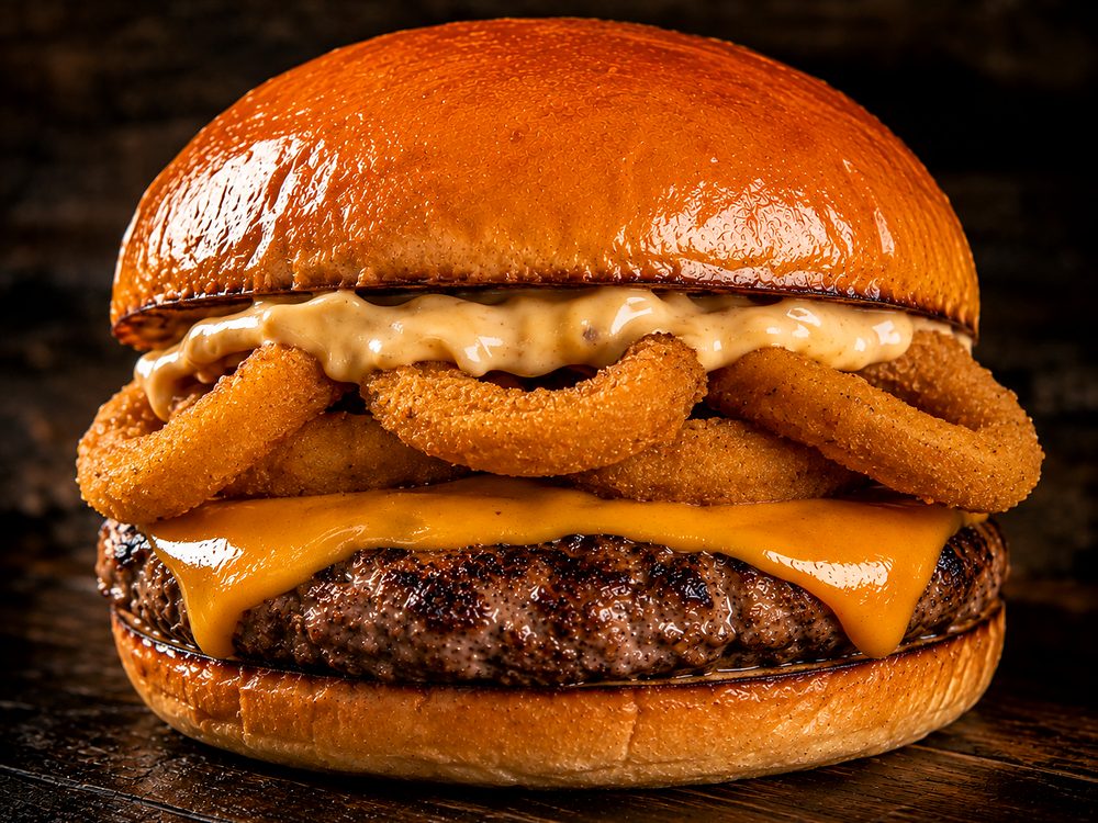 Hambúrguer da Bullgers com anéis de cebola empanados, molho e cheddar
