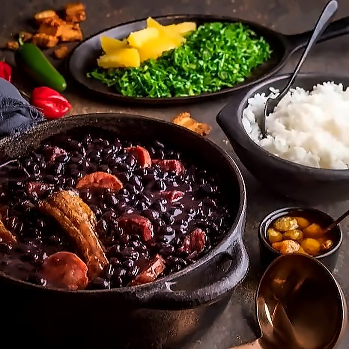 Panela de feijoada com linguiça, couve, laranja, arroz e farofa