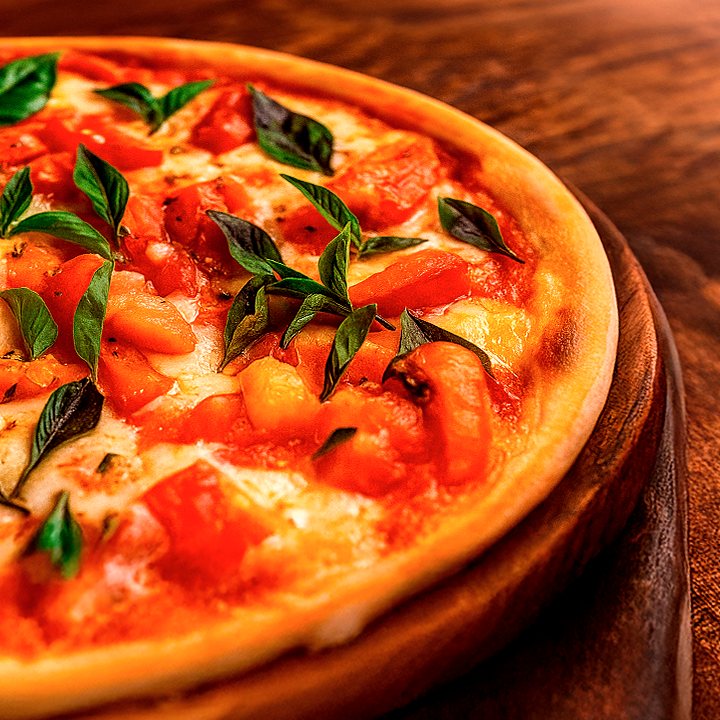 Pizza com tomate, mussarela e folhas de manjericão sobre a massa dourada