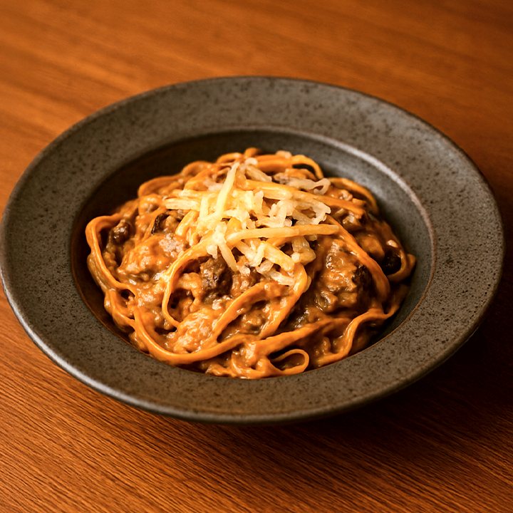 Fettuccine com molho cremoso de carne e queijo ralado no prato fundo